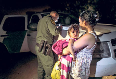 Una mujer con una niña en brazos es detenida por la Patrulla Fronteriza luego de haber cruzado la frontera sur de EE. UU.