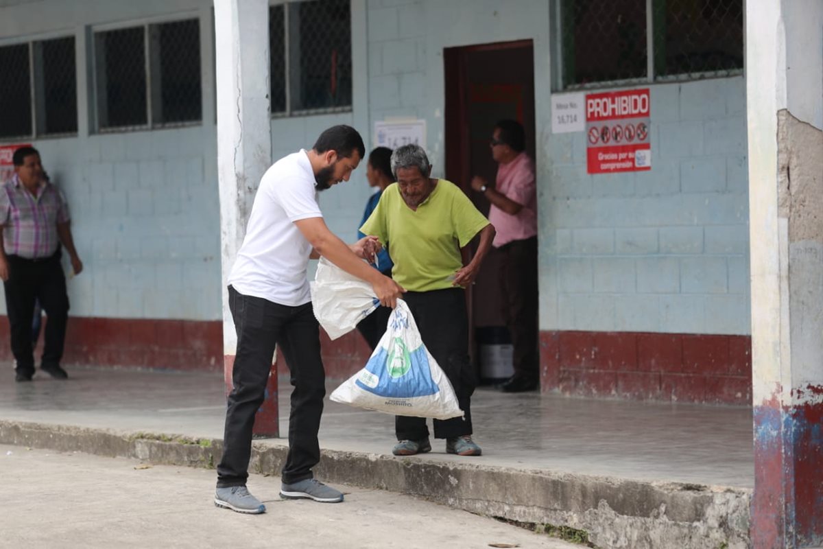 Henrry Pocasangre, enviado especial de Prensa Libre, apoya a don Magdaleno Chún al momento de salir del centro de votación en San Luis Petén. (Foto Prensa Libre: Érick Ávila)