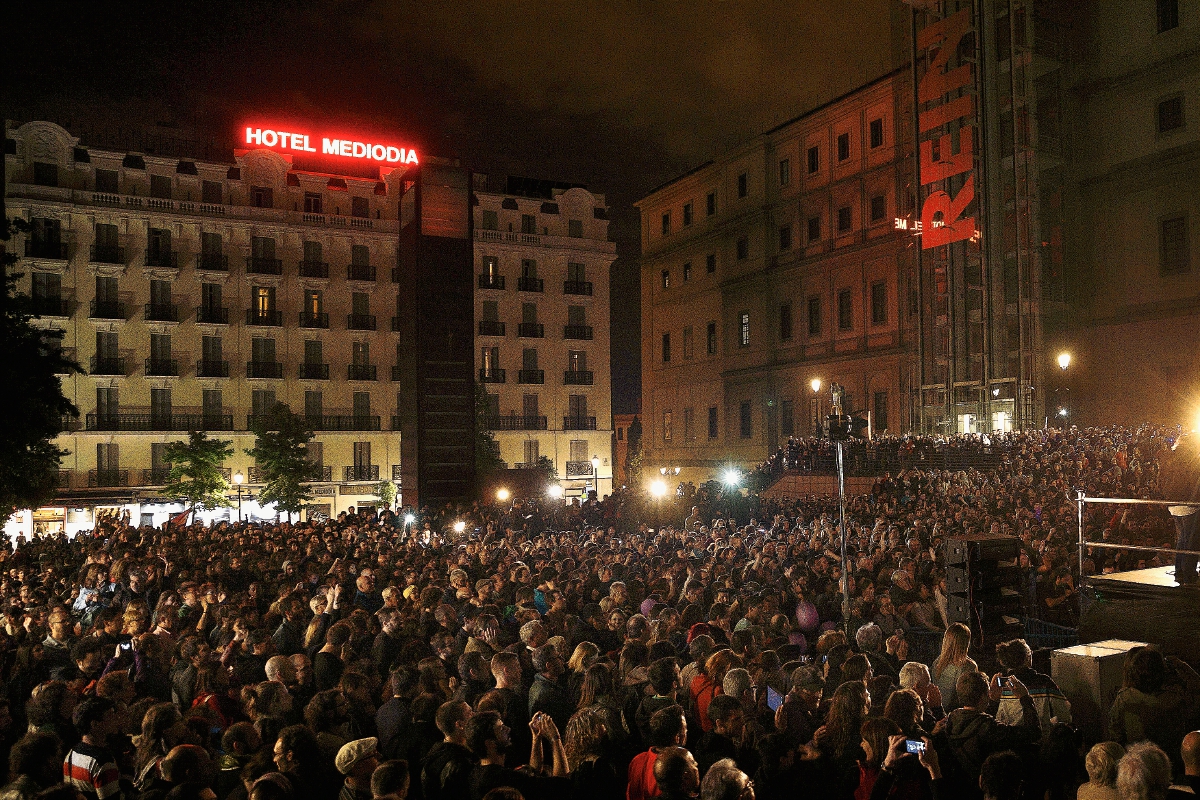 Personas escuchan un discurso de Pablo Iglesias, líder de Podemos quienes celebran los resultados obtenidas en las elecciones municipales de ayer. (Foto Prensa Libre: AP).