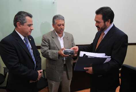 Ovidio Monzón —centro— recibe de Gudy Rivera, diputado del PP, el proyecto de presupuesto del PP. A la izquierda observa el futuro ministro de Finanzas, Pavel Centeno.