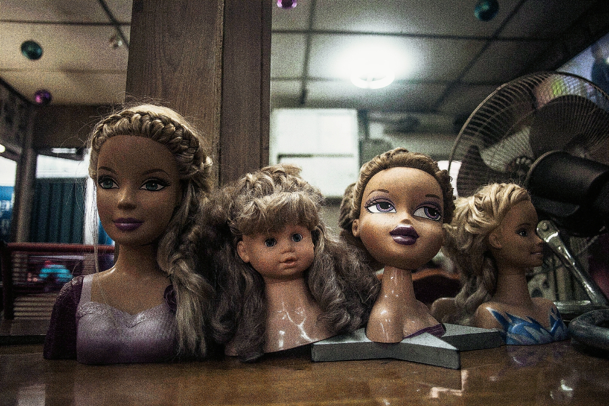 Una peluquería muestra cabezas de muñecas para peinar el cabello en un en el centro de San Salvador, El Salvador. (Foto Prensa Libre:AP)