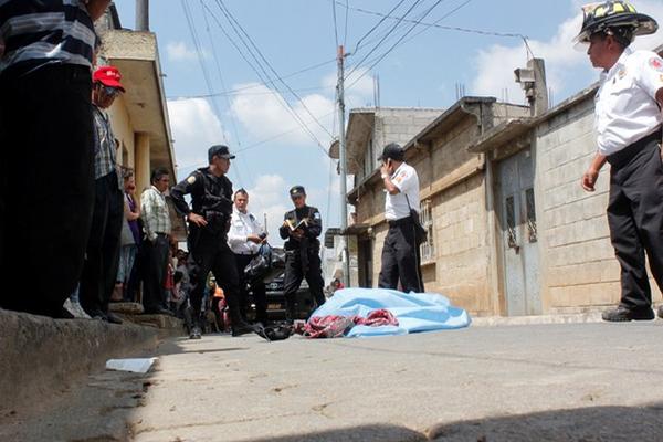 Socorristas y agentes de la PNC permanecen junto al cadáver de Julio Geovani Saquil, quien murió baleado, en Chimaltenango. (Foto Prensa Libre: Víctor Chamalé)