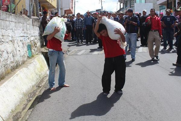 Los dos presuntos delincuentes cargan un costal que contiene piedras, en Totonicapán. (Foto Prensa Libre: Édgar Domínguez) <br _mce_bogus="1"/>