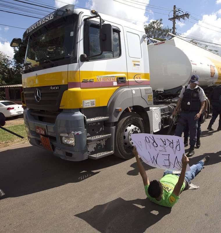 Policías detienen a manifestantes que bloquean la salida de camiones con combustible de la distribuidora de Petrobras. (EFE).