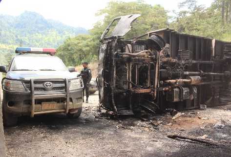 Un agente de la PNC observa el lugar donde fue incendiado un vehículo del Ejército de Guatemala, en la entrada al destacamento militar, en Barillas.
