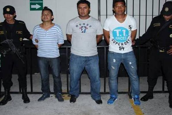 Agentes custodian a los tres hombres capturados. (Foto Prensa Libre: PNC)