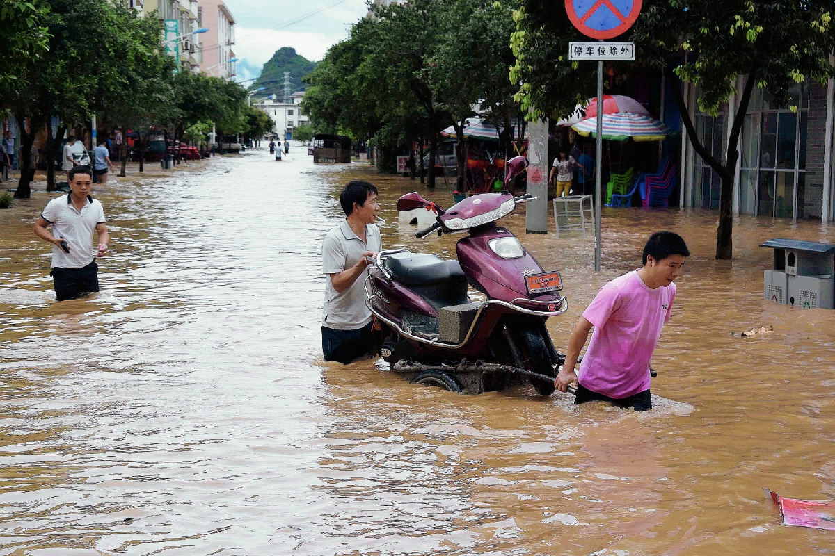 Dos hombres evacúan una de las zonas afectadas por la lluvia. (Foto Prensa Libre: AP).