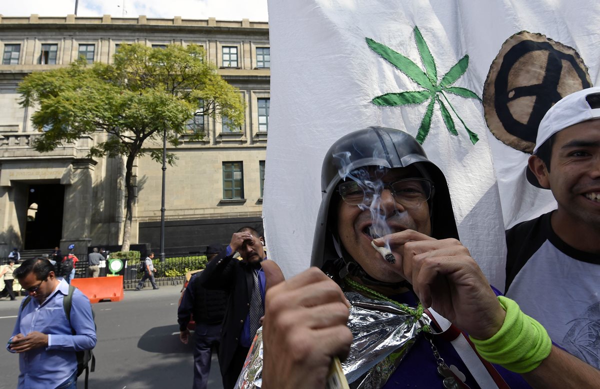 Un hombre fuma marihuana en las afueras de la Suprema Corte de Justicia de México despué de conocer su decisión. (Foto Prensa Libre: AFP).