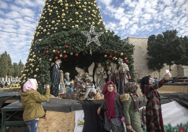 Varias musulmanas se toman fotos delante de un belén cerca de la Basílica de la Natividad. (Foto Prensa Libre: EFE)