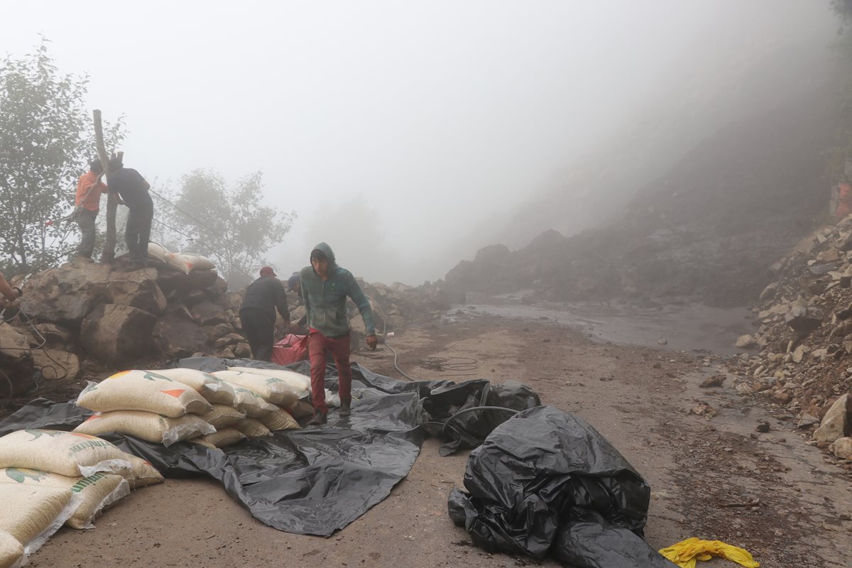 Un hombre camina en medio del derrumbe en la entrada a Sibinal. (Foto Prensa Libre: Whitmer Barrera)