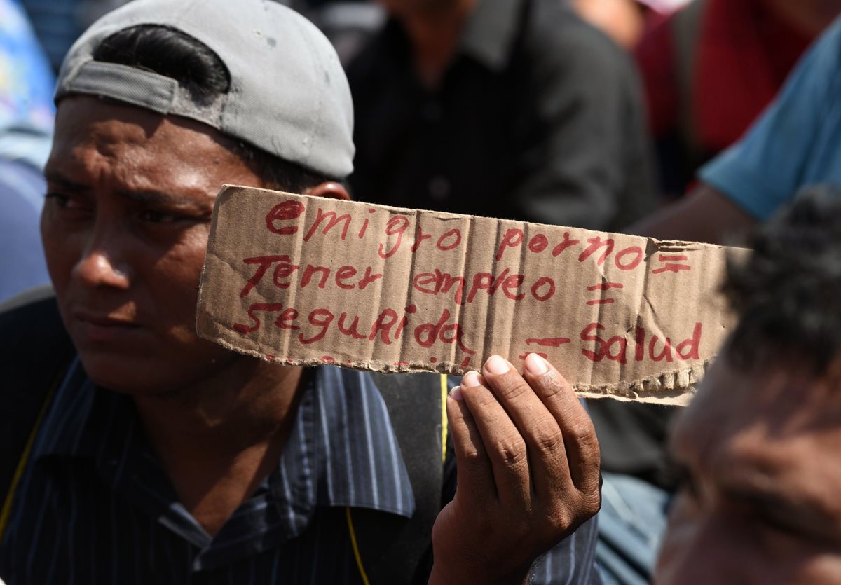 Migrante hondureño muestra un cartel que explica las razones de su migración, entre ellas falta de empleo, salud y seguridad. (Foto Prensa Libre: AFP)