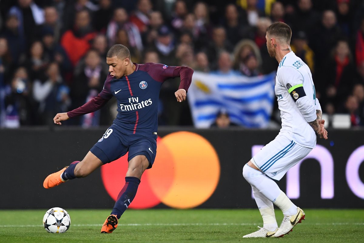 Kylian Mbappe intenta hacer un centro frente a Sergio Ramos.