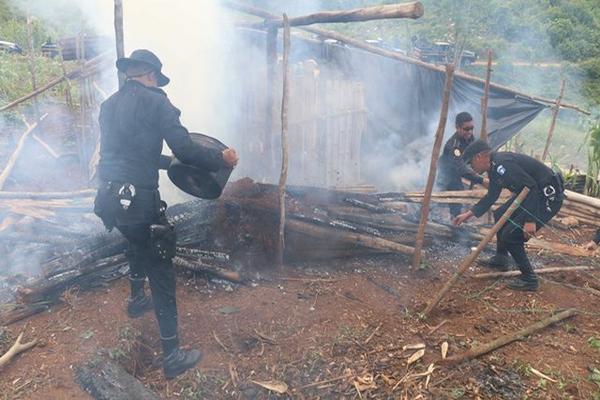 Los agentes policiales que apoyaron el desalojo en aldea Monte Olivo trabajaron en apagar el fuego en algunas viviendas. (Foto Prensa Libre: Eduardo Sam)