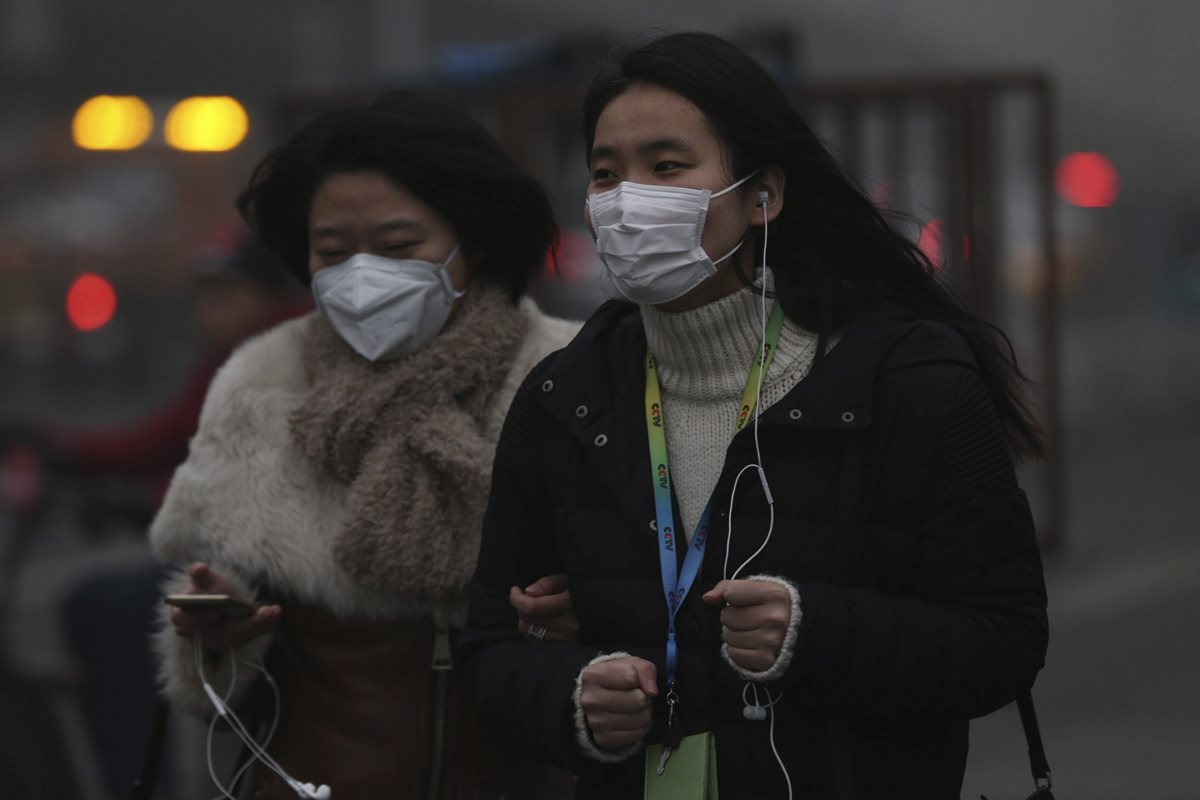 Dos mujeres caminan protegidas con mascarillas por las calles de Pekín, China, en diciembre último. (Foto Prensa Libre: EFE).