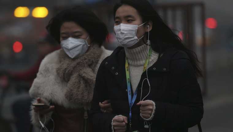 Dos mujeres caminan protegidas con mascarillas por las calles de Pekín, China, en diciembre último. (Foto Prensa Libre: EFE).