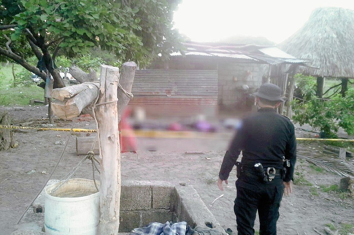 Un agente observa los cuatro cuerpos que quedaron tendidos en el patio de una finca en el sector El Coco, aldea Cuchuapán, Champerico, Retalhuleu. (Foto Prensa Libre: Rolando Miranda)
