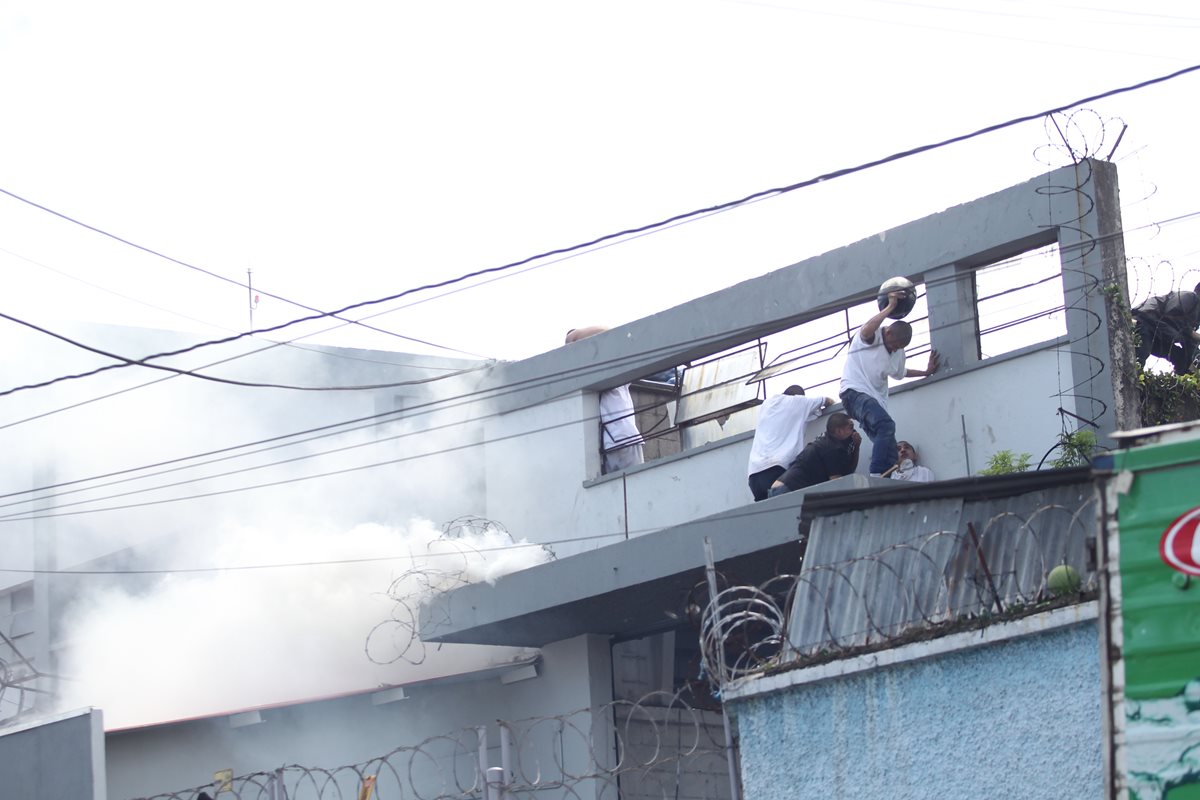Momento en que los internos buscan resguardo en la bodega que tomaron cuando la PNC les lanzó gas. (Foto Prensa Libre: Érick Ávila)