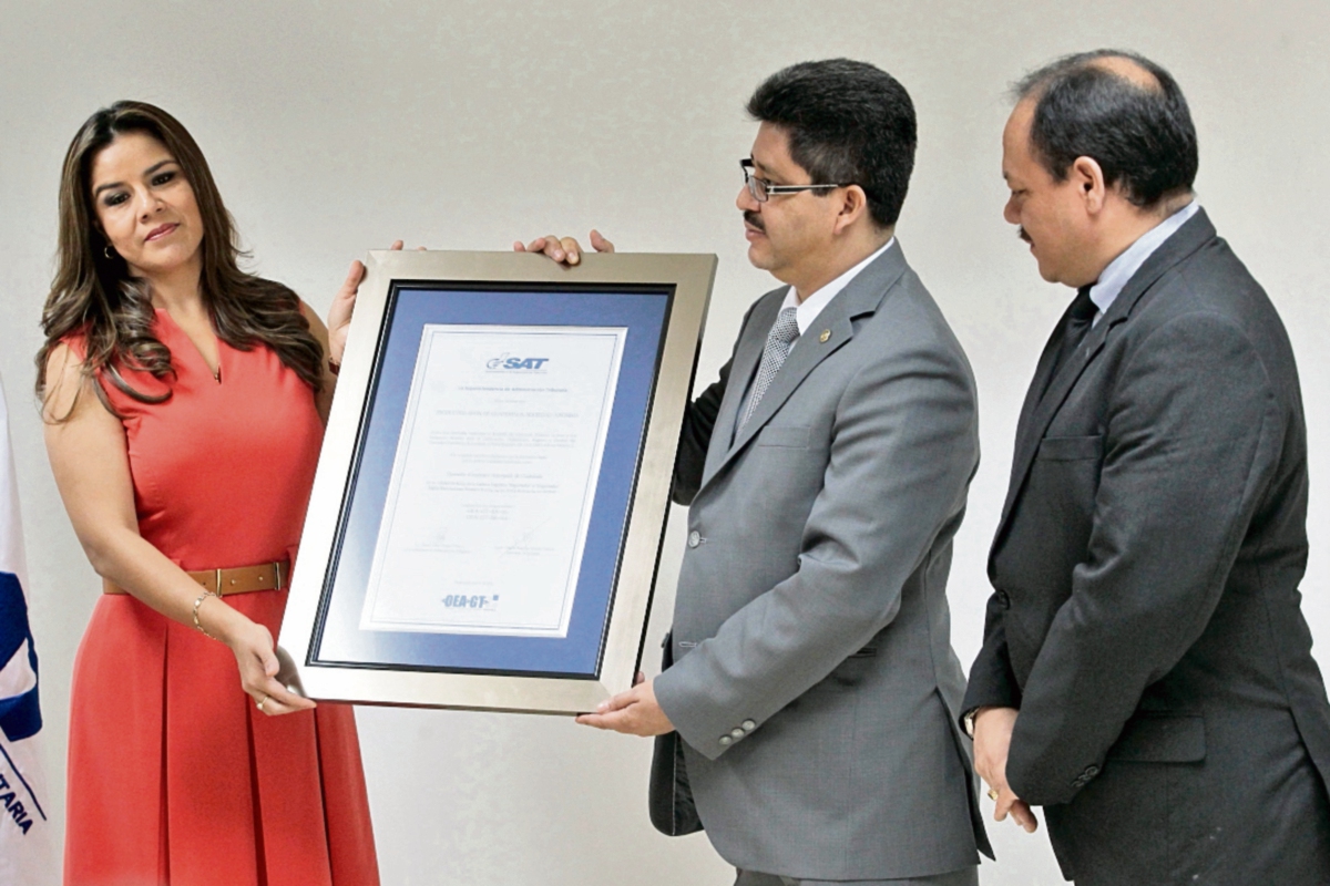La SAT   certificó ayer a la compañía Avon como nuevo Operador Económico. En la foto,  Claudia Méndez  y Omar Franco,  de la SAT y Manfred Castillo de Avon. (Foto Prensa Libre: Álvaro Interiano)