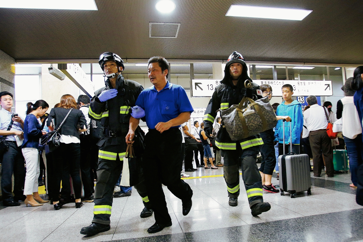 Un pasajero es escoltado por los bomberos después de salir de un tren bala en Odawara,Japón. (Fot Prensa Libre:AP).