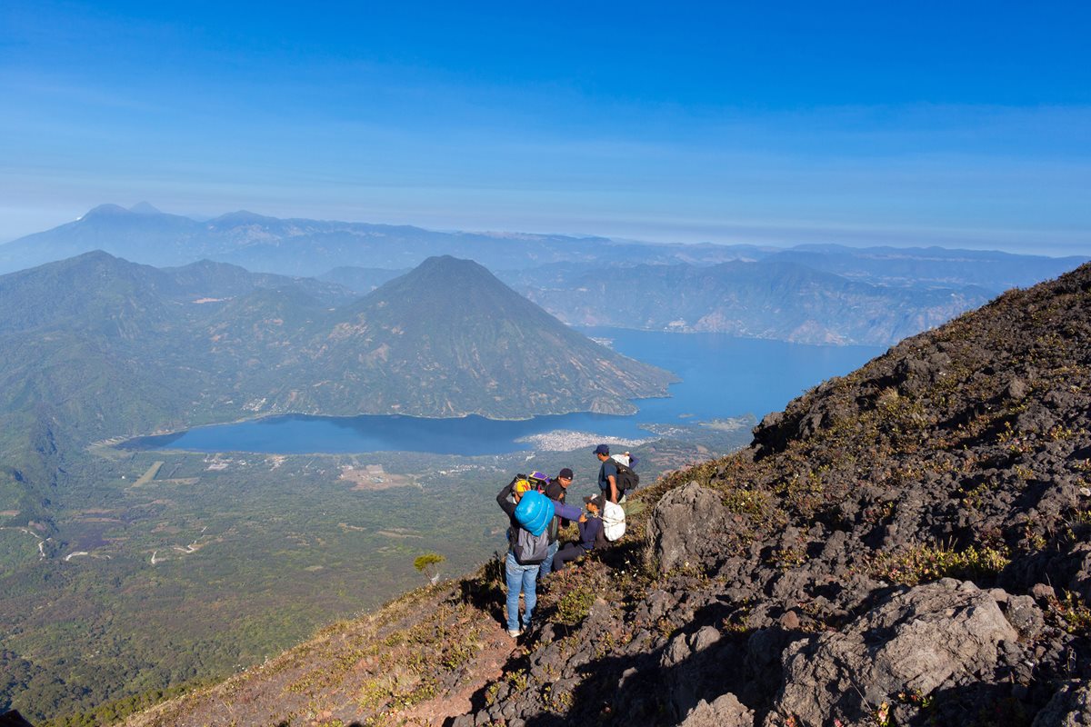 Turistas observan el Lago de Atitlán, desde la cima del volcán Atitlán; al fondo el volcán San Pedro. (Foto Ángel Julajuj)