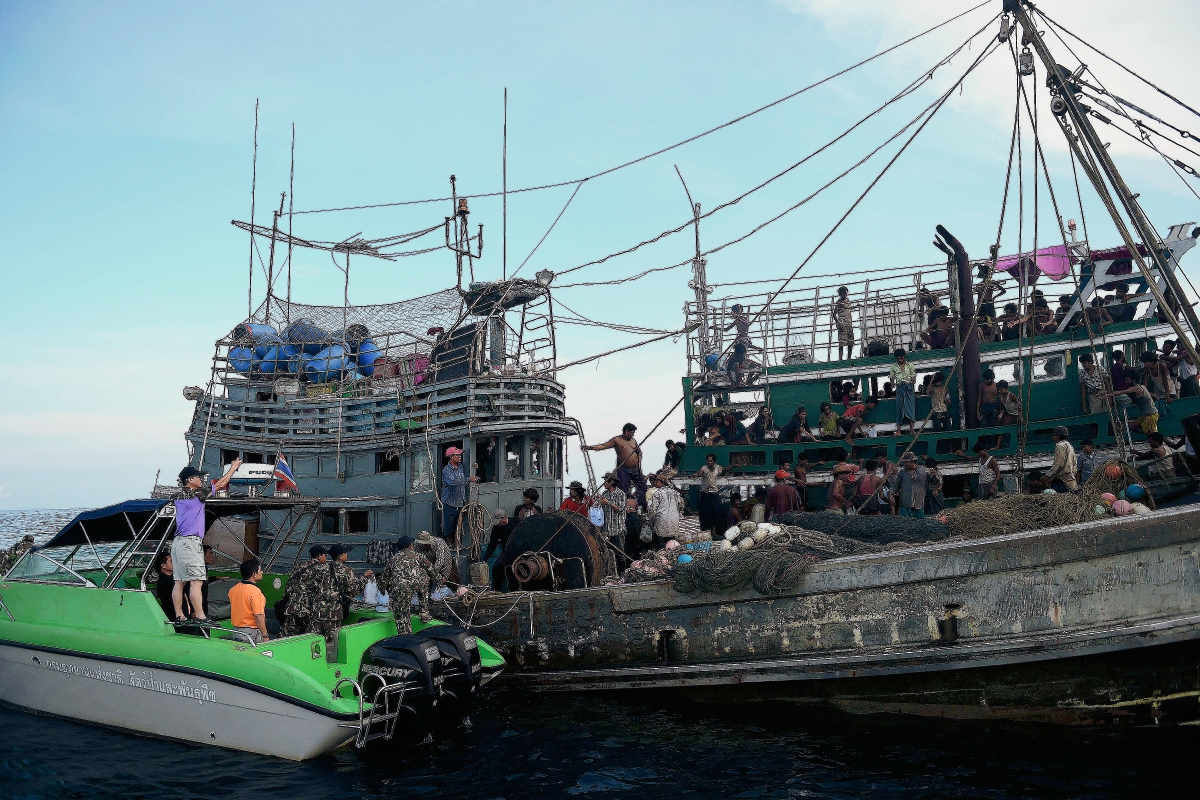 Autoridades proporcionan  el suministro de alimentos a los migrantes rohingya varados en un barco (R) a la deriva en aguas tailandesas. (Foto Prensa Libre:AFP)