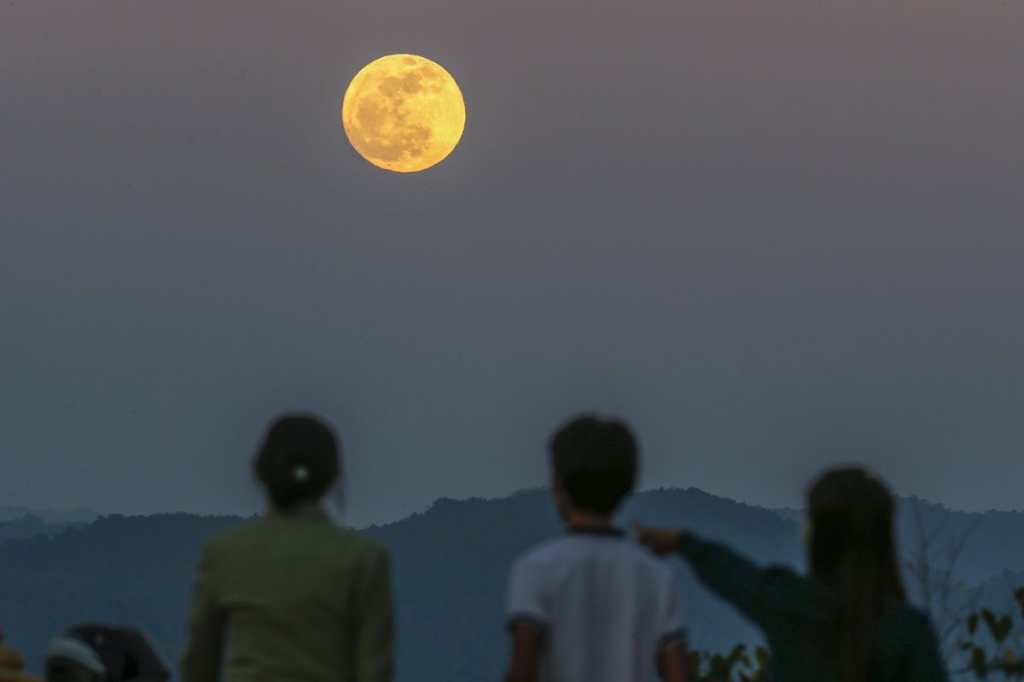 Un grupo de personas observa la luna llena en la montaña Shan, Birmania.