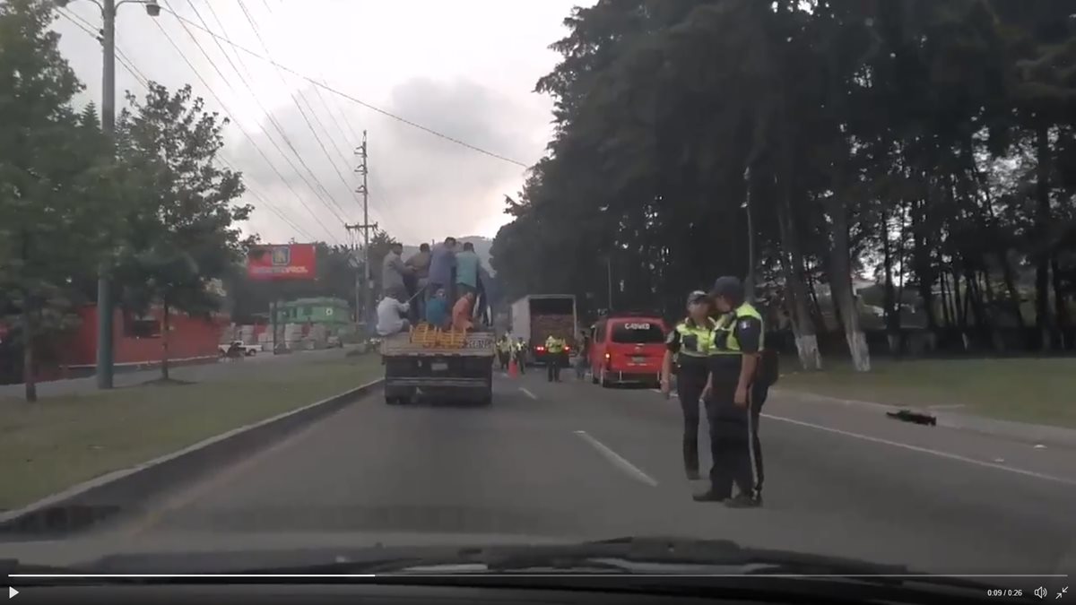 Agentes de la PMT de San Lucas Sacatepéquez ven pasar un camión sobrecargado con personas. (Foto Hemeroteca PL)