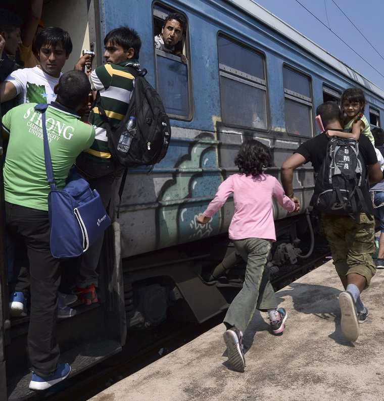 Varios inmigrantes corren para subir a bordo de un tren en dirección a la frontera con Serbia en la estación de Gevgelija en Macedonia. (Foto Prensa Libre: EFE).