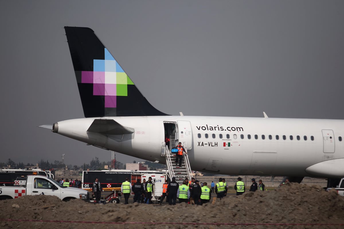 Personal y trabajadores de la aerolínea Volaris descienden del avión luego de la amenaza de bomba. (Foto Prensa Libre: AP).