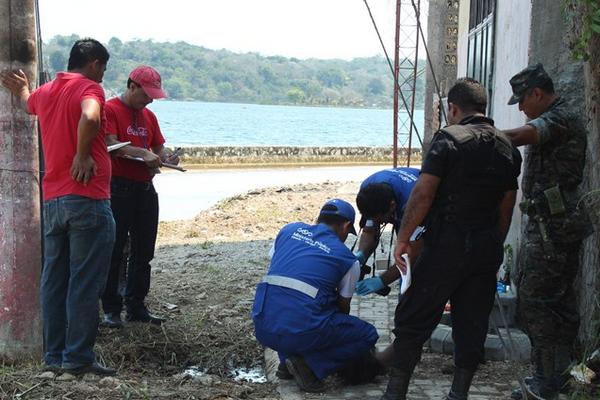 Peritos del Ministerio Público recaban información de víctima en orilla del lago Petén Itzá, en San Benito, Petén. (Foto Prensa Libre: Rigoberto Escobar)<br _mce_bogus="1"/>