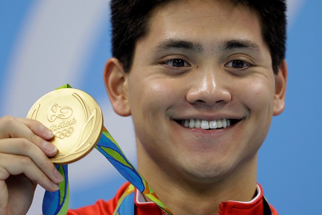 Schooling Joseph sonríe con la medalla de oro después de ganar la prueba de 100 metros mariposa. (Foto Prensa Libre: AFP)