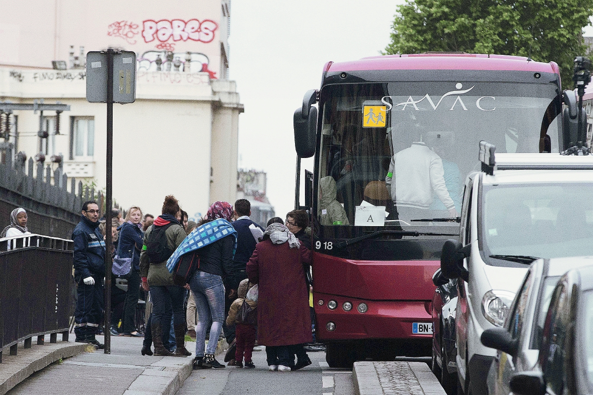 Inmigrantes africanos abordan un autobús después de ser desalojados en París. (Foto Prensa Libre:AFP).