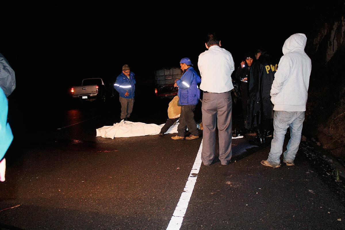 Fiscales del  Ministerio Público examinan el cadáver de un hombre que fue lanzado desde un bus en marcha en Nahualá, Sololá. (Foto Prensa Libre: Ángel Julajuj)