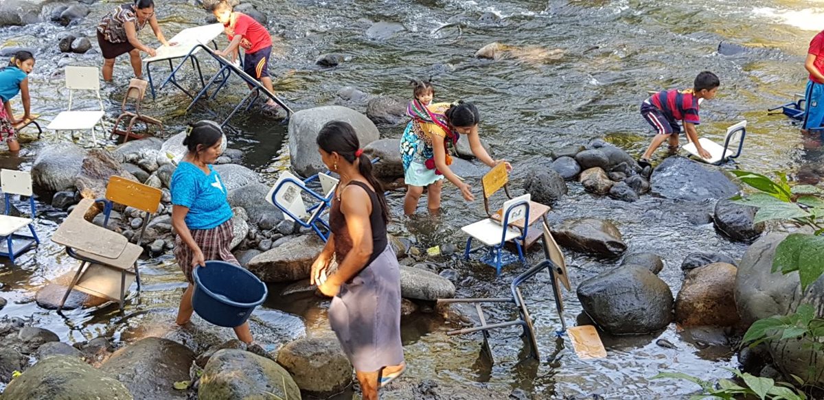 Estudiantes, maestros y padres de familia de la Escuela Rural Mixta La Fortuna de Río Bravo Suchitepéquez, lavan sus escritorios en el río Moca. (Foto Prensa Libre: Cristian Soto)
