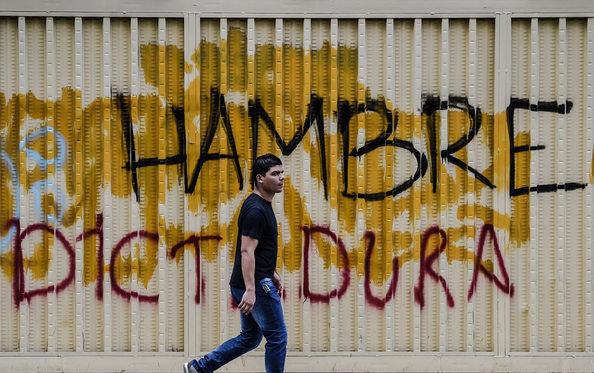 Un venezolano pasa frente a un graffiti en Caracas, durante una huelga general. (Foto Prensa Libre: AFP).
