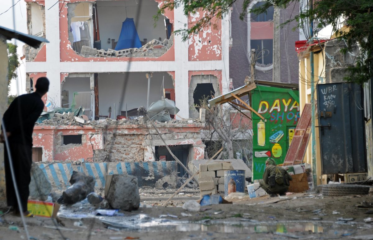 Un curioso observa los movimientos de las fuerzas de seguridad frente al destruido hotel donde ocurrió el atentado en Mogadiscio, Somalia. (Foto Prensa Libre: AFP).