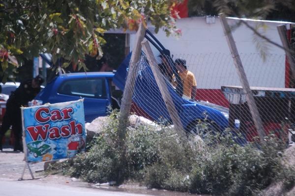 Agentes policiales inspeccionan un vehículo azul que estaba sin placas, y que al parecer era de los hombres que dispararon al aire. (Foto Prensa Libre: Mike Castillo)<br _mce_bogus="1"/>