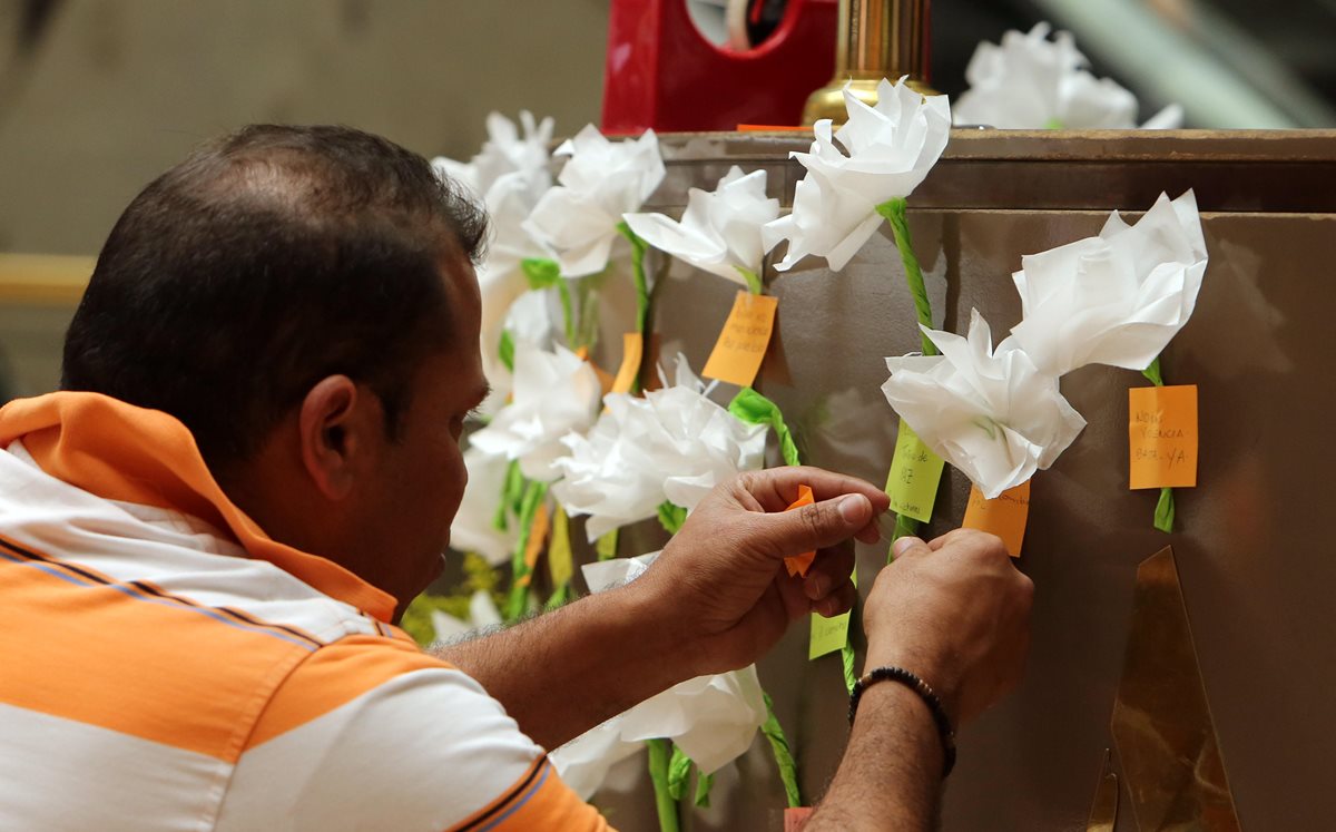 Un visitante al Centro Comercial Andino pone una flor y un mensaje en honor a las víctimas del atentado. (Foto Prensa Libre: EFE).