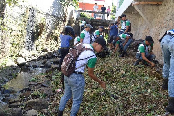 Estudiantes y vecinos limpian las orillas de un río que atraviesa Oratorio, Santa Rosa.