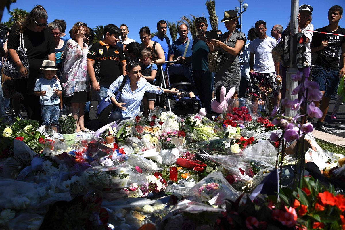 Personas colocan flores en una calle de Niza en homenaje a las víctimas del atentado. (Foto Prensa Libre: AFP).