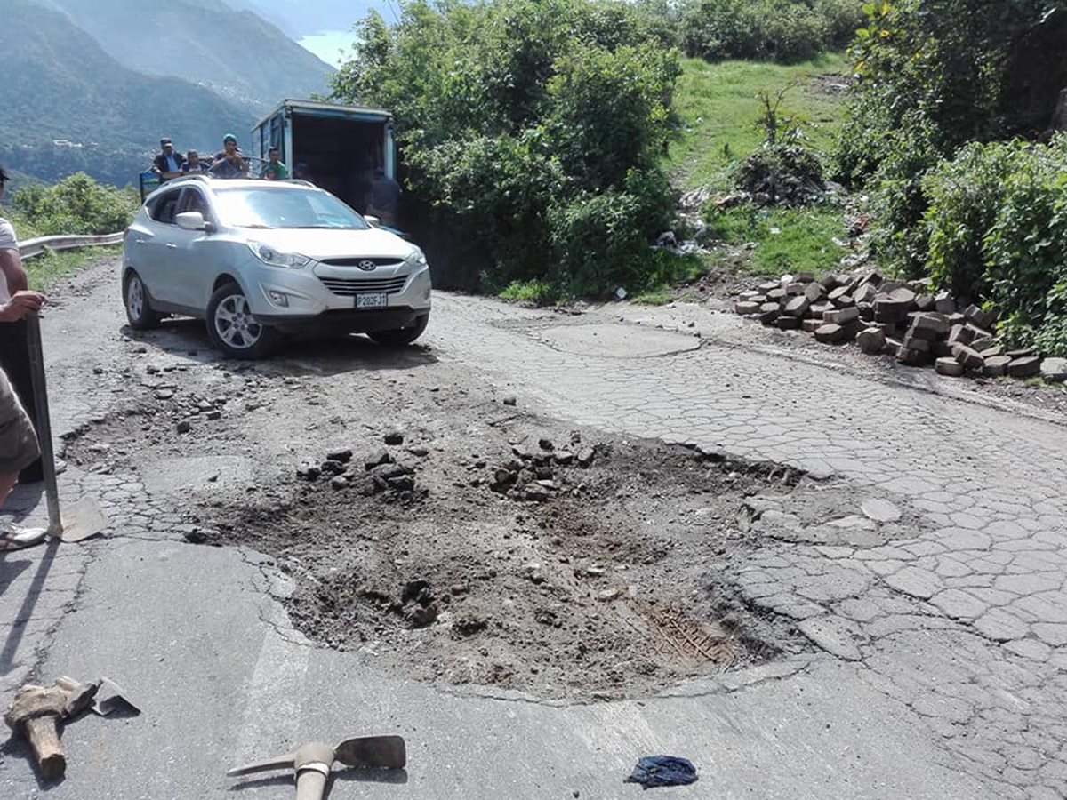 Los agujeros dificultan transitar en la carretera que rodea cinco municipios de la cuenca del Lago de Atitlán, Sololá,. (Foto Prensa Libre: Ángel Julajuj)