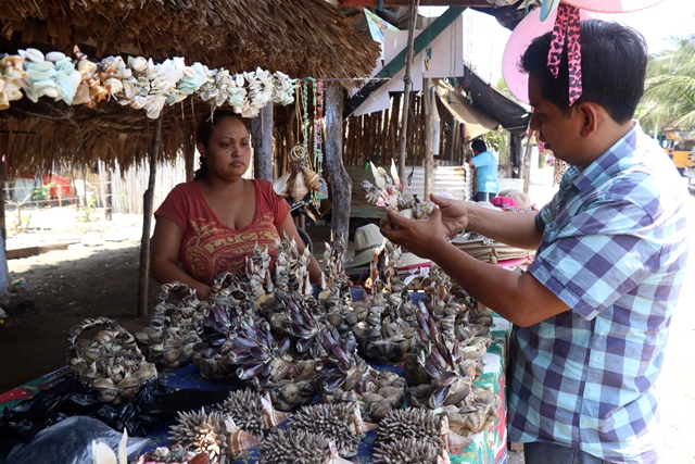 Una comerciante de Champerico ofrece artesanías con productos marinos a un visitante. (Foto Prensa Libre: Rolando Miranda)
