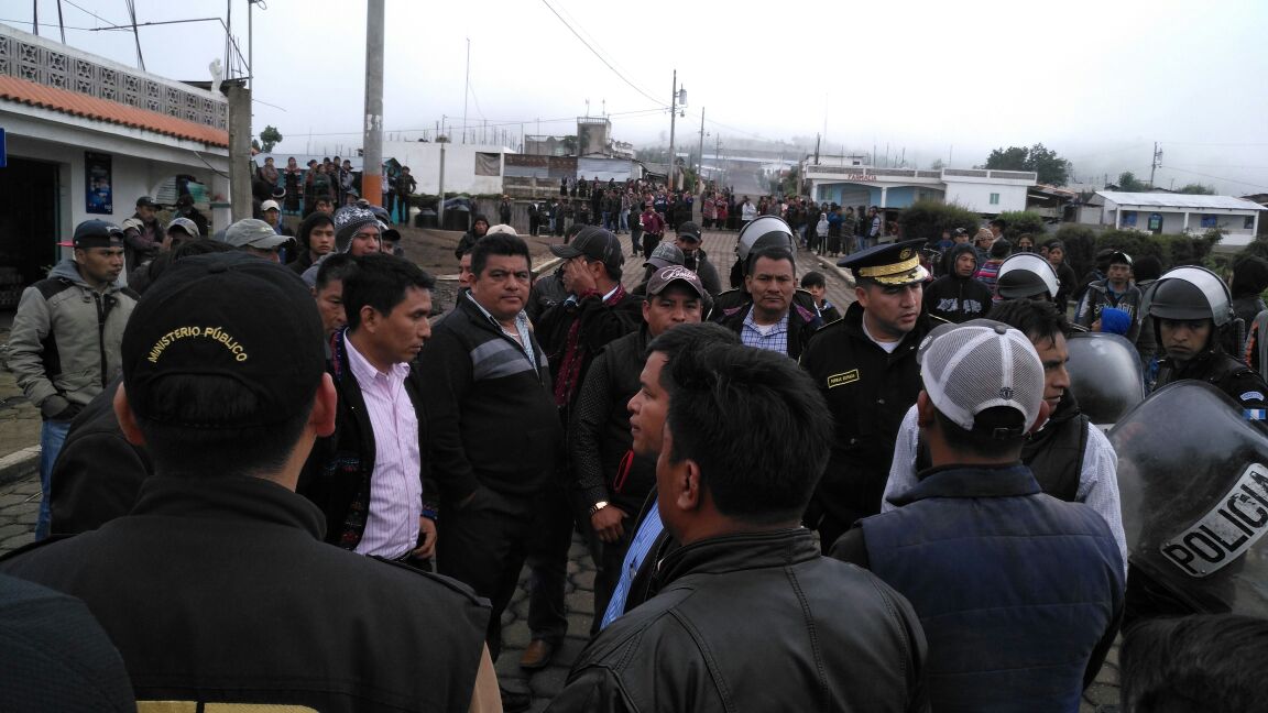 Agentes de la PNC y fiscales del MP dialogan con los comunitarios para intentar retomar el control. (Foto Prensa Libre: Ángel Julajuj).
