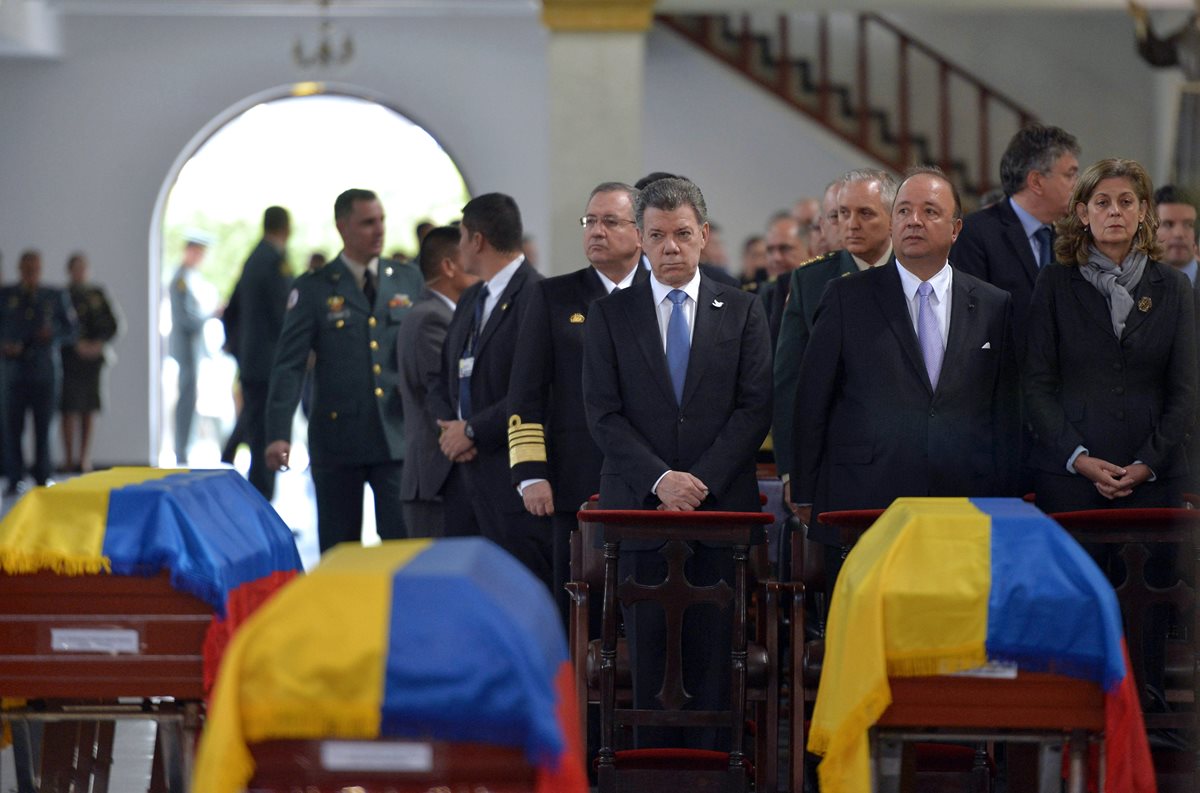 El presidente colombiano, Juan Manuel Santos (centro), participa en las honras fúnebres a los soldados que murieron en un enfrentamiento con al ELN. (Foto Prensa Libre: EFE).