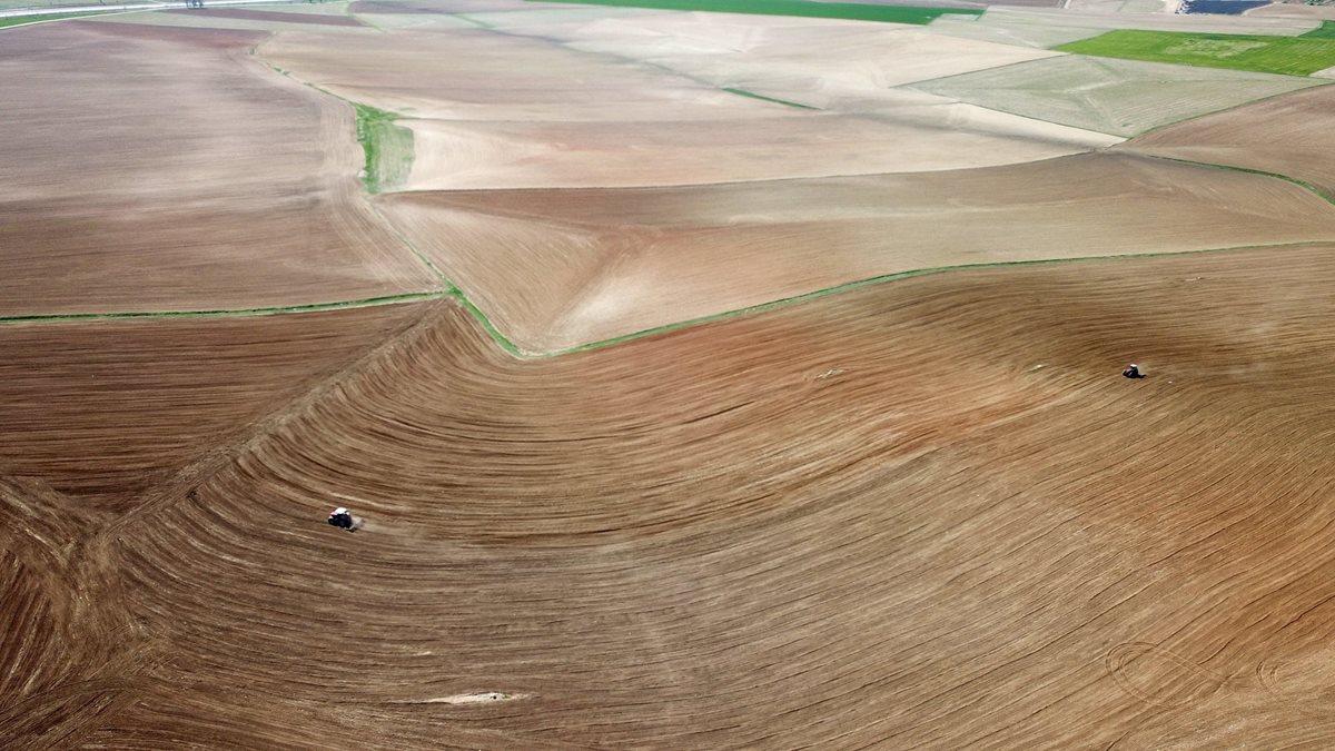 Fotografía aérea tomada desde un dron que muestra a unos agricultores mientras trabajan la tierra con sus tractores en Konya, Turquía. (Foto Prensa Libre: EFE)