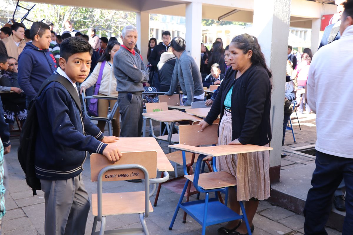 Padres de familia y estudiantes del Instituto Nacional Experimental de San Pedro Sacatepéquez, San Marcos, esperan que les asignen salones de clases para trasladar los escritorios. (Foto Prensa Libre: Whitmer Barrera)