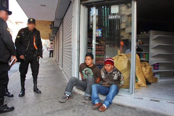 Dos presuntos saqueadores fueron aprehendidos cuando intentaban escapar con mercadería robada en una farmacia. (Foto Prensa Libre: PNC)<br _mce_bogus="1"/>