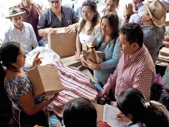 Mauricio Méndez, alcalde de San Pedro La Laguna —con camisa roja a cuadros—, supervisa entrega de bolsas de papel a comerciantes del mercado. (Foto Prensa Libre: Ángel Julajuj)