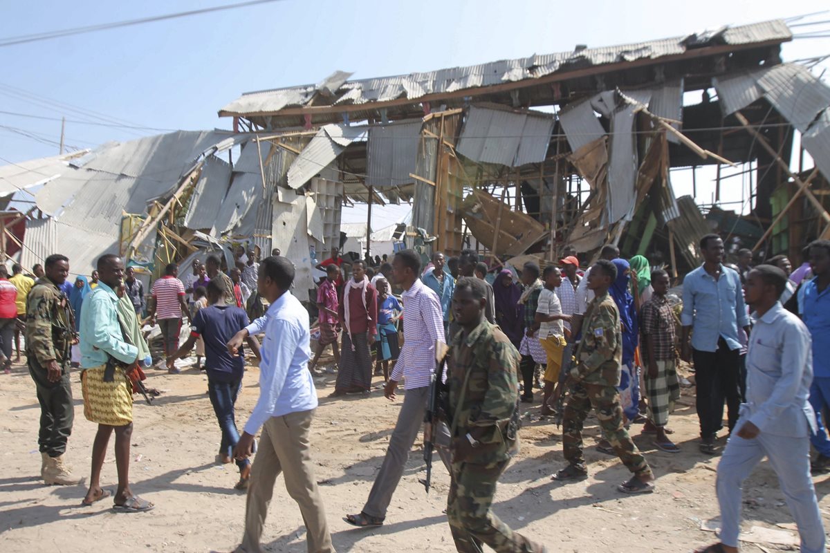 Soldados somalíes y curiosos se reúnen en el lugar de una explosión.(Foto Prensa Libre:EFE).