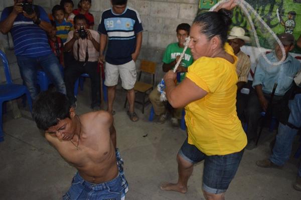La mujer azota a su hijo, a quien pobladores acusan de robo de motocicletas. (Foto Prensa Libre: Jorge Tizol).